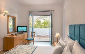 a bedroom with a bed and a television and a balcony at Mitsis Norida in Kardamaina