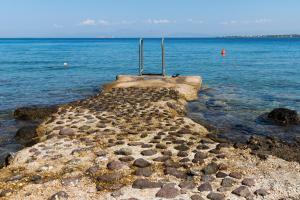 a stone pier in the middle of the water at Perdika Mare Guesthouse in Perdika