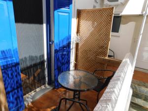 a table and chairs sitting on a balcony with a window at Perdika Mare Guesthouse in Perdika