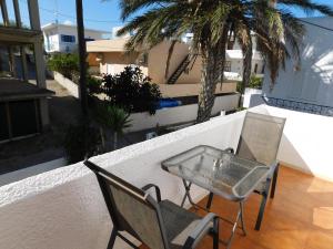 a table and chairs on a balcony with palm trees at Perdika Mare Guesthouse in Perdika