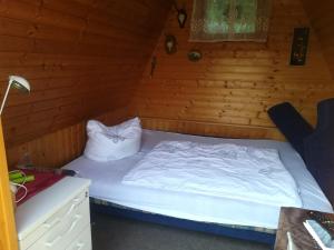 a bed in a room with a wooden wall at Ferienhaus am Wald in Loissin