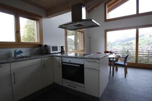 eine Küche mit weißen Schränken, einem Tisch und Fenstern in der Unterkunft Région de GSTAAD, charmant chalet duplex de 80m2 in Zweisimmen