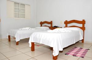 2 Betten mit weißer Bettwäsche in einem Zimmer in der Unterkunft Hotel Carolina 2- próximo ao hospital Regional, hospital Mario Palmério, Hospital São Marcos in Uberaba