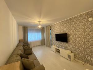 a living room with a couch and a tv on a wall at Luxury Cosmo Apartments Sinaia in Sinaia