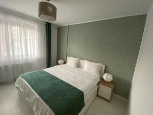 a bedroom with a bed with a green and white blanket at Luxury Cosmo Apartments Sinaia in Sinaia