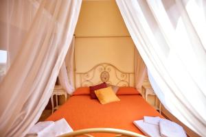 a bedroom with a bed with orange sheets and curtains at Agriturismo Podere Casa al Vento in Montepulciano