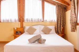 una camera da letto con letto, lenzuola bianche e finestre di Nevesole Folgarida Resort Aparthotel a Dimaro