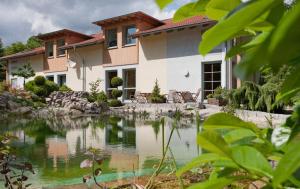 uma casa com um lago em frente a uma casa em Landhaus Tonmühle em Ilsenburg