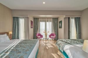 Habitación de hotel con 2 camas y 2 sillas rosas en Taximist Hotel, en Estambul