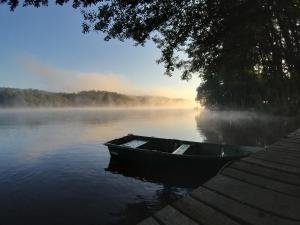 a boat sitting on a lake in the mist at Przystań na Zagórzu - Apartamenty nad jeziorem in Drezdenko