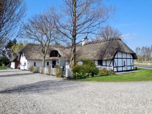 uma casa branca com um telhado de palha numa estrada em Naboløs Bed'n Kitchen - Nyborg em Bovense