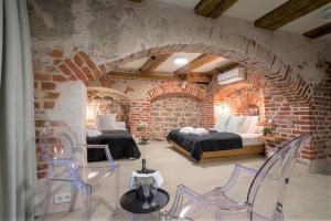 a bedroom with two beds and chairs in a brick wall at Rixwell Old Riga Palace Hotel in Riga
