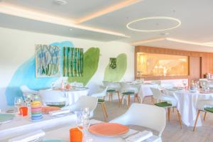 a dining room with white tables and white chairs at Hotel Restaurant La Vague de Saint Paul in Saint Paul de Vence