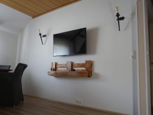 eine Wand mit einem TV und einem Kreuz an einer Wand in der Unterkunft Mosea in Zeltingen-Rachtig