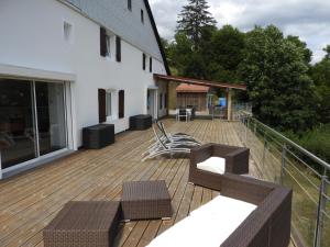 a deck with chairs and tables on a house at La Parenthèse Vosgienne in Bussang