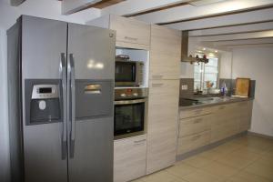 uma cozinha com um frigorífico de aço inoxidável e armários em La Parenthèse Vosgienne em Bussang