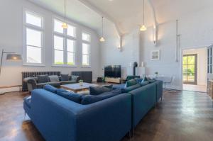 una gran sala de estar con sofás azules y TV. en Luxury Victorian school with views of Harbour, en Fowey