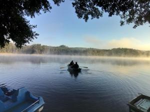 dwoje ludzi w łodzi na jeziorze z mgłą w obiekcie Przystań na Zagórzu - Apartamenty nad jeziorem w mieście Drezdenko