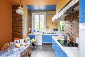 cocina con armarios azules y pared de ladrillo en Gîte de la Bove, en Bouconville-Vauclair