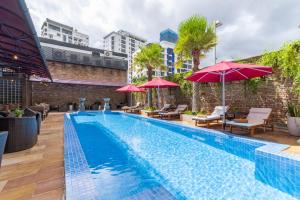 a swimming pool with chairs and umbrellas next to a building at Anik Boutique Hotel & Spa on Norodom Blvd in Phnom Penh