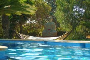 a hammock next to a pool with a buddha statue at Agroturismo Finca Sa Tanca in Cala d´Or