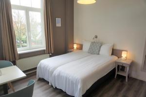 a bedroom with a white bed and a window at Hotel Bon Accueil in De Haan