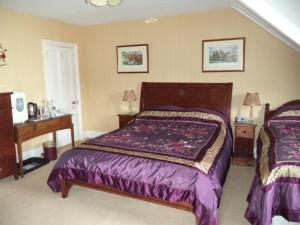 a bedroom with a bed with purple sheets and two tables at Britten House in Lowestoft