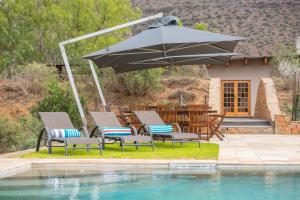 a group of chairs and an umbrella next to a pool at Glen Harry Game Reserve in Graaff-Reinet