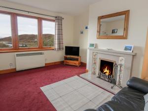 a living room with a fireplace and a television at Taigh Na Talia - 2 Sandholm in Mallaig