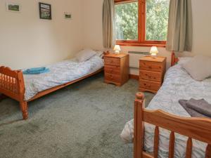 a bedroom with two beds and two dressers and a window at Taigh Na Talia - 2 Sandholm in Mallaig