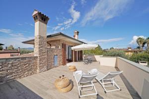 a patio with chairs and an umbrella and a building at Villa Riai in Moniga
