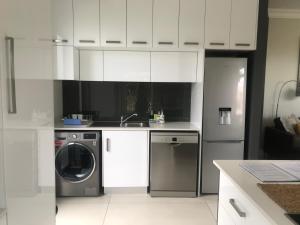 a kitchen with white cabinets and a washing machine at The Cottage on Cordia 2 Bedroom self catering 2km from Umhlanga beach in Durban