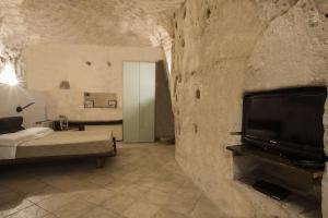 a bedroom with a bed and a tv in a stone wall at Residence San Pietro Barisano in Matera