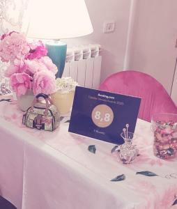 un tavolo con fiori rosa e un cartello sopra di Il Roseto a Frosinone