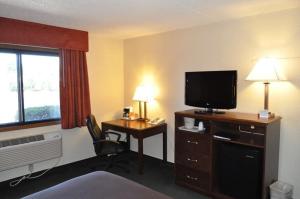 a hotel room with a desk with a television and a bed at AmericInn by Wyndham Plymouth in Plymouth