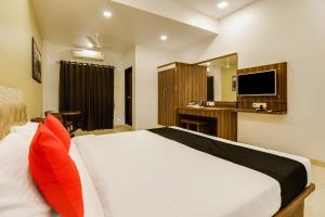a bedroom with a bed and a desk and a television at Hotel Om Inn - Talegaon Dabhade in Talegaon Dābhāde