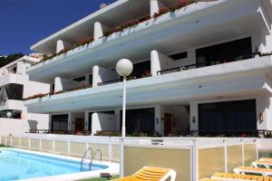 a large white building with a swimming pool and chairs at Apartamentos Gelimar in Puerto Rico de Gran Canaria