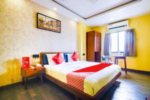 a hotel room with a bed and a desk and a window at Kiaan Inn in Kolkata