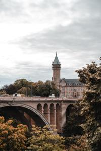 ibis Styles Arlon Porte du Luxembourg في آرلون: مبنى فيه برج ساعة وجسر