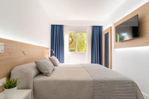 ein Schlafzimmer mit großem Bett und Fernseher in der Unterkunft Aparthotel Ciudad Laurel in Cala Millor