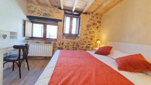 a bedroom with a bed and a desk and two windows at Casas del Castillo, 4 in Ávila