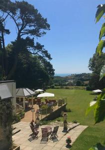 eine Terrasse mit Stühlen und Sonnenschirmen auf einem Feld in der Unterkunft Penmorvah Manor Hotel in Falmouth