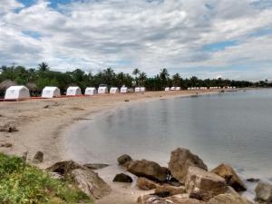 una playa con tiendas blancas y rocas en el agua en Hostal Santa Clara en San Antero