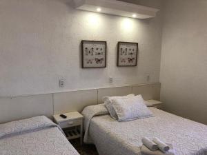 a bedroom with two beds and two pictures on the wall at Hotel Rivadavia in Piriápolis