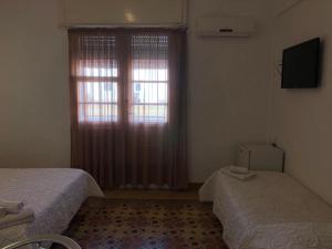 1 dormitorio con 2 camas y ventana en Hotel Rivadavia, en Piriápolis