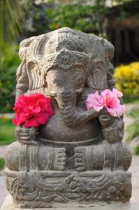 une statue en pierre avec deux fleurs roses sur elle dans l'établissement Kimbas Bungalows Mancora, à Máncora