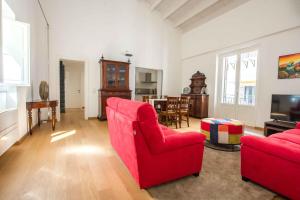 a living room with two red chairs and a television at Magione Apartment with Terrace by Wonderful Italy in Palermo