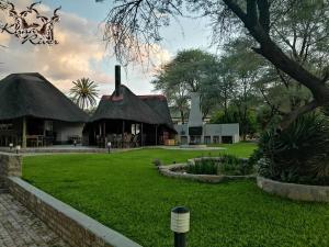 a house with a thatched roof and a yard at Khan River Lodge in Wilhelmstal