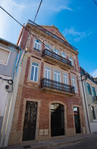 um antigo edifício de tijolos com uma varanda numa rua em Arte Nova Guesthouse na Covilhã