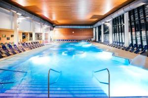 a large swimming pool with chairs in a building at Apartment Leggero in Moravske-Toplice